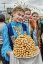 Girls in national festive clothes holding plate with Bashkir dessert at Sabantuy holiday