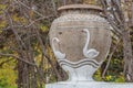 Yekaterinburg, Sverdlovsk Russia - 09 28 2018: A beautiful old gray stone vase with white swans is in the park in autumn