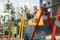 Yelling little boy riding on swings on a children playground. He is flying high