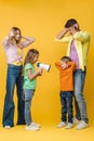 Yelling into megaphone on brother while parents closing ears on yellow Royalty Free Stock Photo