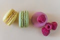 Yelllow, green and pink french macaroons and raspberries