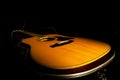 Yellow acoustic guitar lying in a hard case in the dark on a black background. Wooden stringed instrument illuminated by