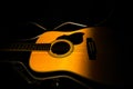 Yellow acoustic guitar lying in a hard case in the dark on a black background. Wooden stringed instrument illuminated by