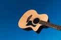 Yellow acoustic wooden guitar against blue sky.