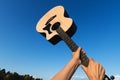 Yellow acoustic wooden guitar in girl hands against blue sky on sunset.