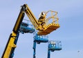 Yellow aerial working platform of cherry picker in front of other three blue. Royalty Free Stock Photo