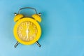 Yellow alarm clock close-up on a blue background. It`s Blue Monday time