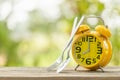 Yellow alarm clock, Fork, and spoon on wooden table with green outdoor nature blur background. Eight o'clock, Time for eating Royalty Free Stock Photo