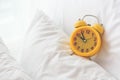 Yellow alarm clock on white bed background. Travel and Vacation Royalty Free Stock Photo