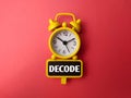 Yellow alarm clock and wooden board with word DECODE