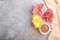 Yellow anf purple day-lilies cup of coffee on a gray concrete background, with orange textile. Top view, copy space Royalty Free Stock Photo