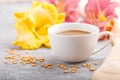 Yellow anf purple day-lilies cup of coffee on a gray concrete background, with orange textile. Side view, close up Royalty Free Stock Photo