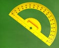The yellow angle protractor on green chalkboard in classroom.