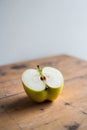 Yellow apple cut in half on wooden surface. Royalty Free Stock Photo