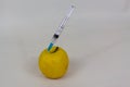 Yellow apple injected with a syringe closeup view isolated on white background