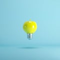 Yellow apple light bulb floating on blue background Royalty Free Stock Photo