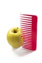 Yellow apple and a red plastic comb stuck Royalty Free Stock Photo