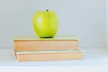 A yellow apple sitting on top of a stack of books Royalty Free Stock Photo