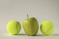 Yellow apple between two tennis balls Royalty Free Stock Photo