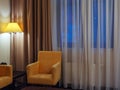 A yellow armchair next to a luminous floor lamp in the corner of the room near the window. Fragment of the interior of a Royalty Free Stock Photo