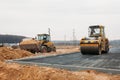 Yellow asphalt compactor at work and orange bulldozer with sand in the background Royalty Free Stock Photo