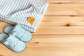 Yellow autumn leaf over striped fuzzy blanket and funny cat face blue slippers over natural wood surface. Warm fleece bedding and