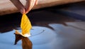 Yellow autumn leaf ship in children hand, boy play in water pond Royalty Free Stock Photo