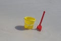 A yellow baby bucket and a red shovel stand on the sand by the sea Royalty Free Stock Photo