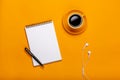 On a yellow background, a cup of black coffee with a notepad and headphones Royalty Free Stock Photo