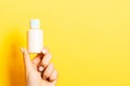 Yellow background with female hand holding cosmetics bottle and copy space for your design Royalty Free Stock Photo