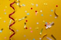 On a yellow background lies a swirling ribbon and festive confetti