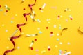 On a yellow background lies a swirling ribbon and festive confetti