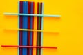 On a yellow background are multi-colored cocktail tubes, on a heap of vertical tubes are three horizontal