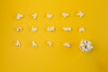 Yellow background, rows of popcorn and bowl with popcorn, top view