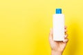 Yellow background with woman`s hand holding a cosmetics bottle with copy space Royalty Free Stock Photo