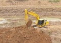 A yellow backhoe is digging a big pond Royalty Free Stock Photo