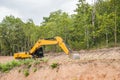 Yellow backhoe excavating soil and sand