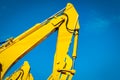 Yellow backhoe with hydraulic piston arm against clear blue sky. Heavy machine for excavation in construction site. Hydraulic Royalty Free Stock Photo
