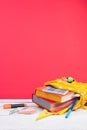 Yellow backpack with white polka dots with different colorful stationery on table. Bright Red background. Back to school Royalty Free Stock Photo