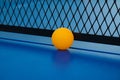 Yellow ball hits the bottom of the net on a blue pingpong table Royalty Free Stock Photo