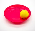 Yellow ball on red and pink plastic dish on white Royalty Free Stock Photo