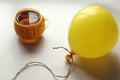 Yellow balloon with a cup of tea in a knitted outfit, side view-the concept of good mood on gray days Royalty Free Stock Photo