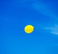 yellow balloon flying into sunny blue sky Royalty Free Stock Photo