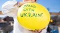 Yellow balloon with the inscription stand with Ukraine in children hands