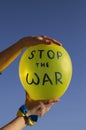 Yellow balloon with the inscription stop the war against the blue sky in female hands. Solidarity with Ukraine