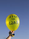 Yellow balloon with inscription stop the war against blue sky on sunny day. Solidarity with Ukraine