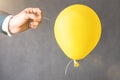 yellow balloon. Man hold needle directed to air balloon. Royalty Free Stock Photo