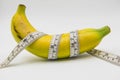 Yellow banana and Measuring tape wrapped around on white background Royalty Free Stock Photo