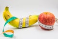 Yellow banana and red apple Measuring tape wrapped around on white background Royalty Free Stock Photo