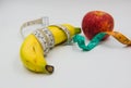 Yellow banana and red apple Measuring tape wrapped around on white background Royalty Free Stock Photo